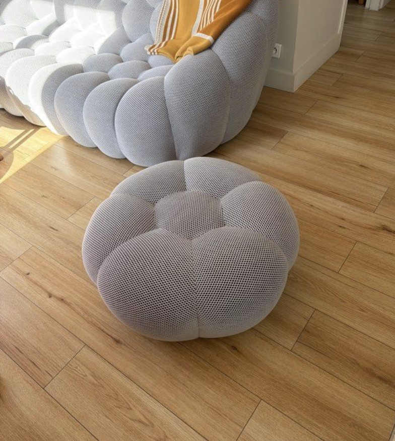 Pouf clair assorti à un canapé aux formes organiques dans un intérieur lumineux