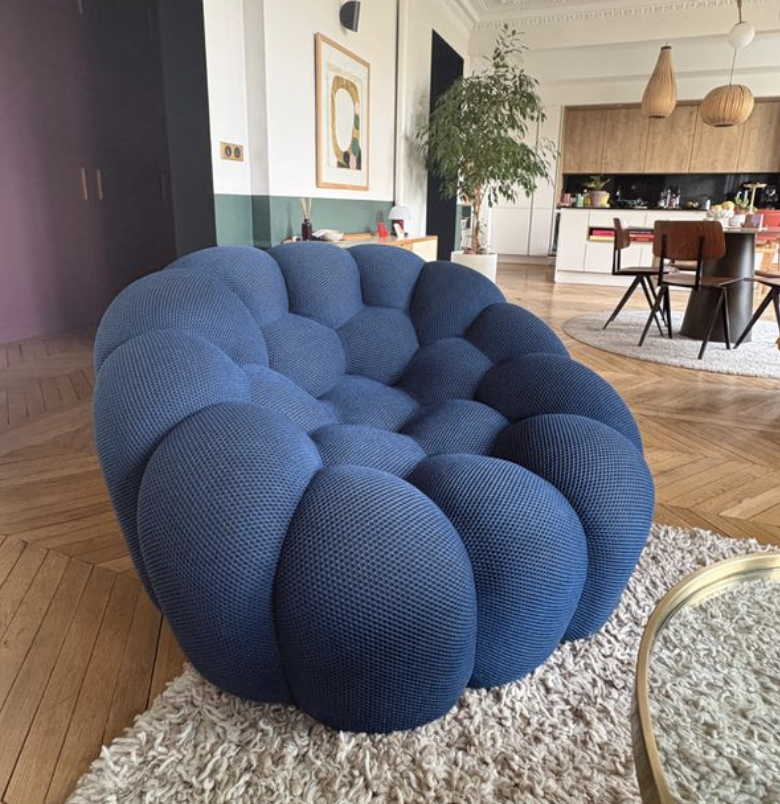 Canapé bleu aux formes organiques installé dans un salon ouvert