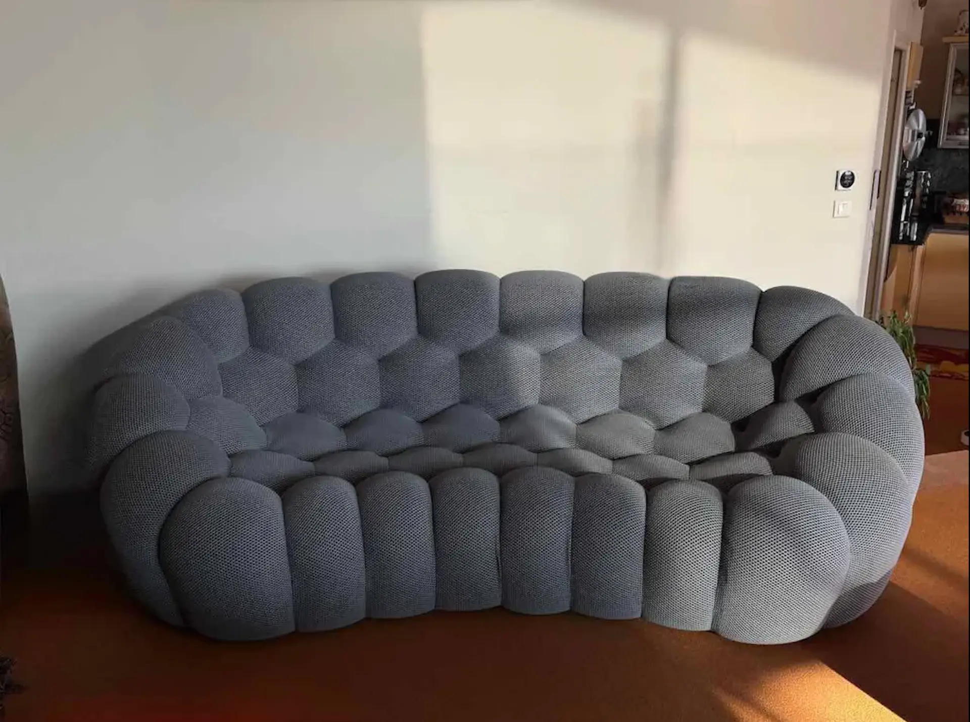 Canapé aux formes organiques, teinte grise, installé dans un salon
